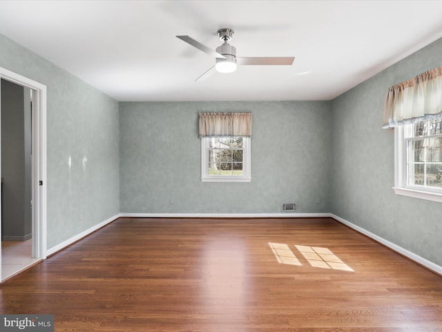 spare room with ceiling fan, visible vents, plenty of natural light, and wood finished floors