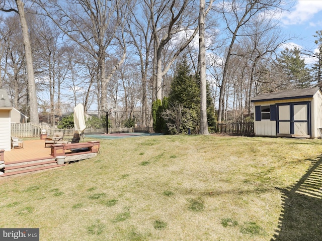 view of yard with a shed, fence, an outdoor structure, and a deck