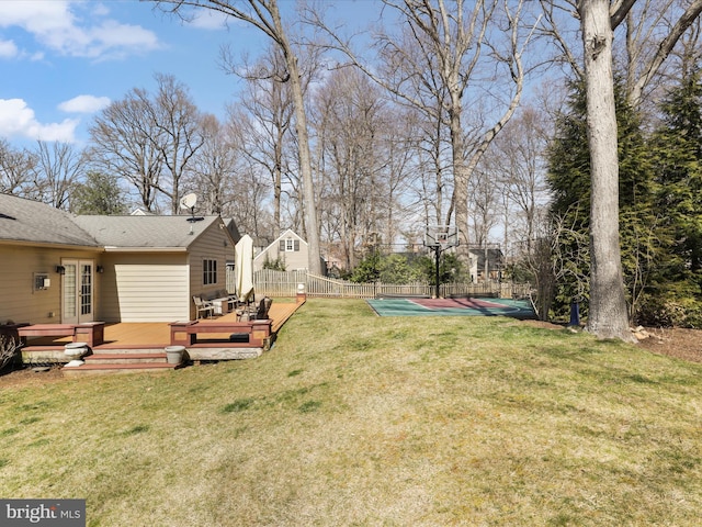 view of yard featuring basketball hoop, a deck, and fence