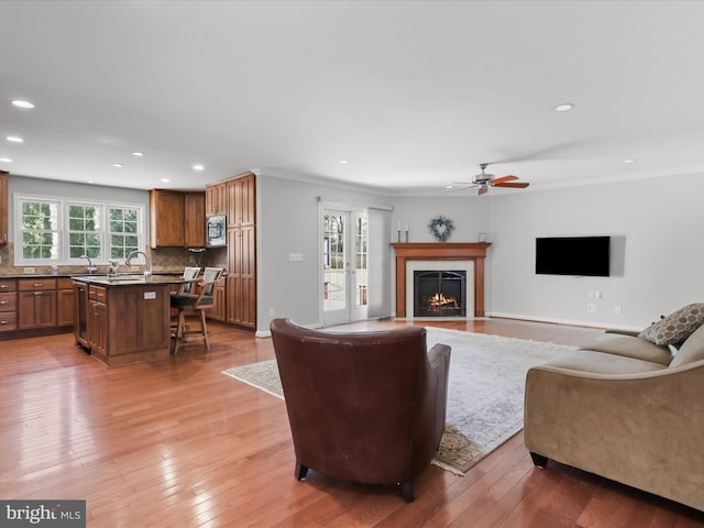 living room with a fireplace with flush hearth, recessed lighting, and light wood-type flooring