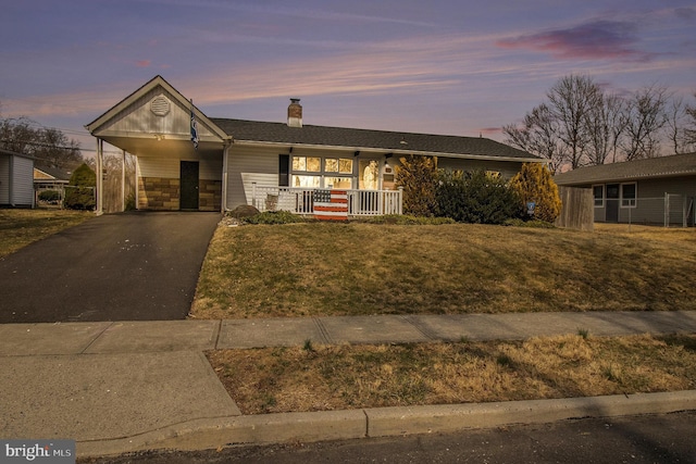 ranch-style house featuring a porch, driveway, a front yard, and a carport