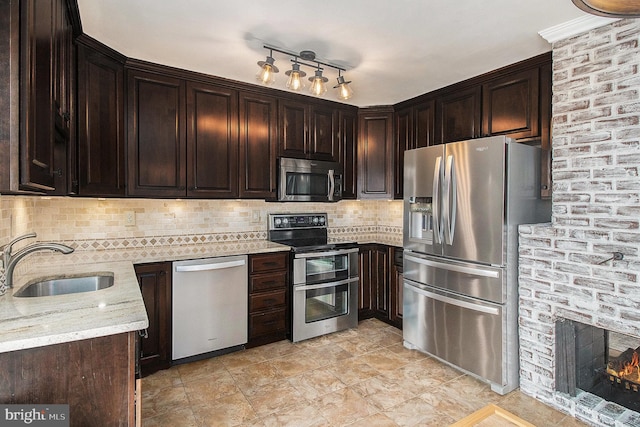 kitchen with light stone counters, backsplash, appliances with stainless steel finishes, and a sink