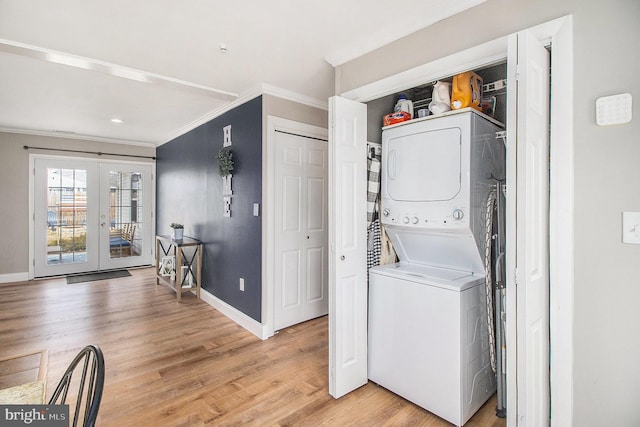 laundry area with ornamental molding, laundry area, light wood-style flooring, stacked washer and clothes dryer, and french doors