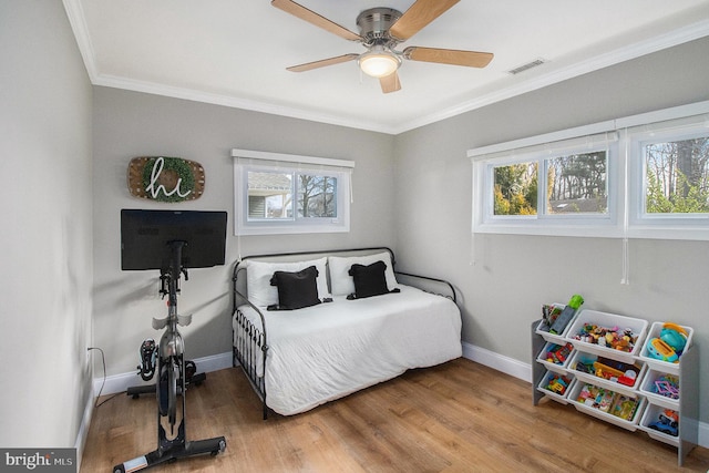 bedroom with visible vents, ornamental molding, wood finished floors, baseboards, and ceiling fan