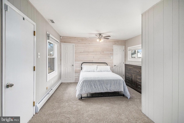 carpeted bedroom featuring a baseboard radiator, wooden walls, visible vents, and ceiling fan