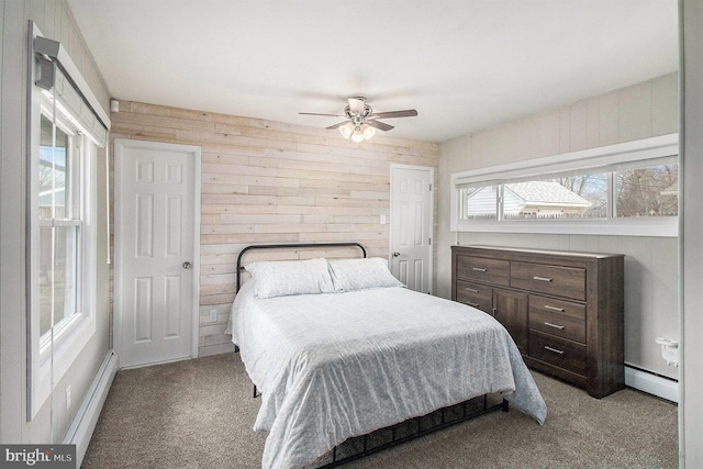 bedroom featuring a baseboard heating unit, carpet, wooden walls, and a ceiling fan