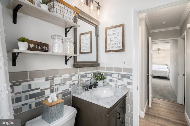 bathroom with wood finished floors, tile walls, vanity, and ornamental molding