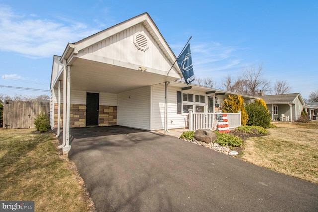 view of front of house with an attached carport, aphalt driveway, a porch, and a front lawn