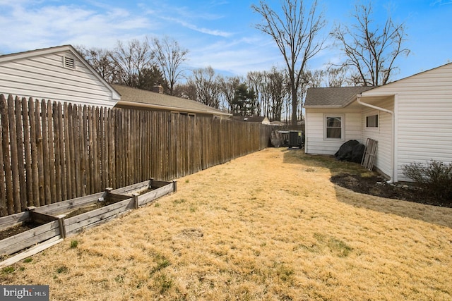 view of yard with a vegetable garden, a fenced backyard, and central AC