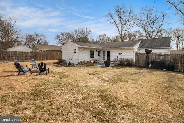 rear view of property featuring a yard, a patio area, a fenced backyard, and an outdoor fire pit