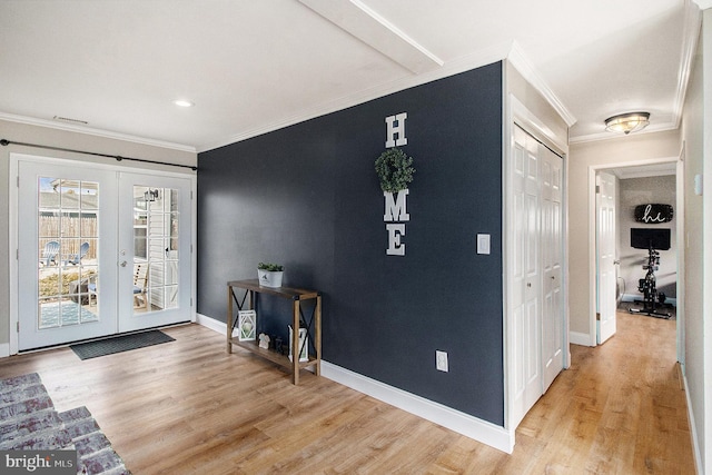 foyer entrance with light wood finished floors, french doors, crown molding, and baseboards