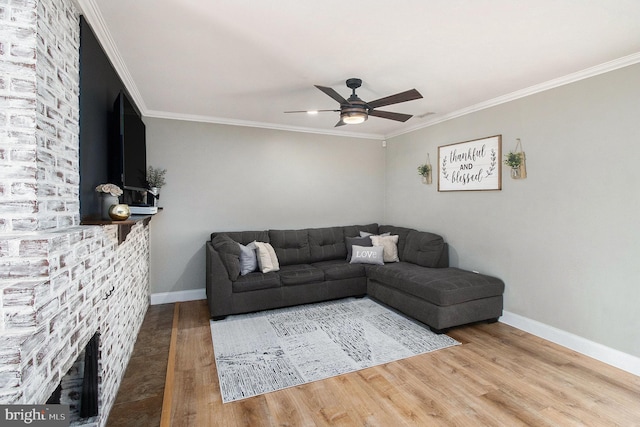 living area featuring crown molding, wood finished floors, baseboards, and ceiling fan