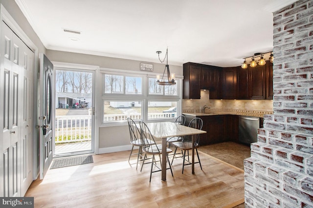 dining room with crown molding, light wood-style flooring, baseboards, and visible vents