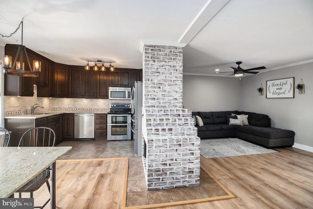 kitchen featuring backsplash, crown molding, dark brown cabinetry, light wood-style floors, and stainless steel appliances