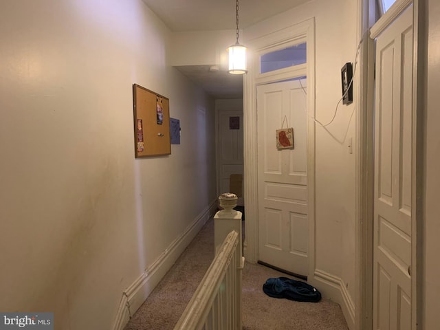 hallway with an upstairs landing, light carpet, and baseboards