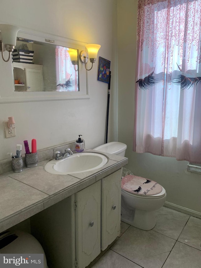 half bathroom featuring vanity, tile patterned floors, toilet, and a healthy amount of sunlight