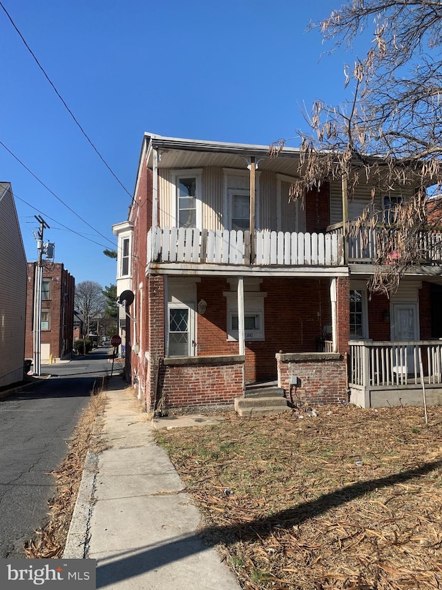 view of front of house with aphalt driveway, a balcony, and brick siding