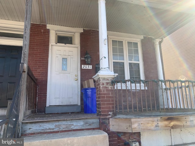 entrance to property with brick siding and a porch