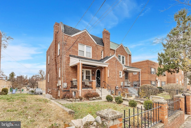 view of front of property with brick siding, fence, roof with shingles, covered porch, and a chimney