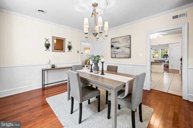 dining room with a chandelier, visible vents, crown molding, and wood-type flooring