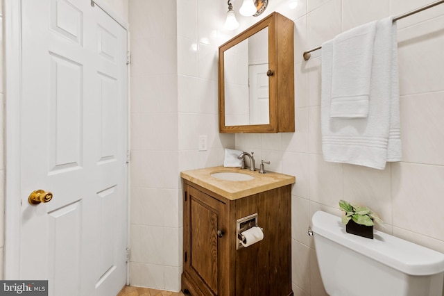 bathroom featuring toilet, tile walls, and vanity