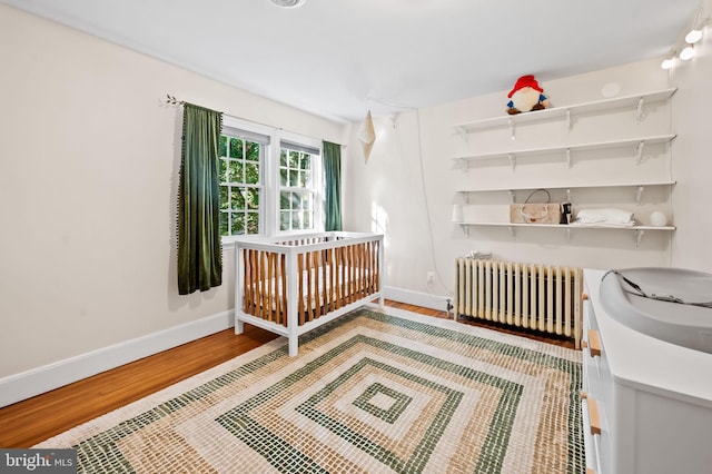 bedroom featuring radiator heating unit, wood finished floors, and baseboards