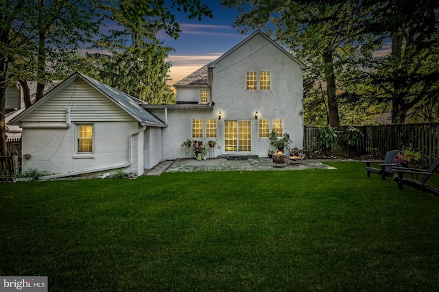 back of property with stucco siding, a patio, a lawn, and fence