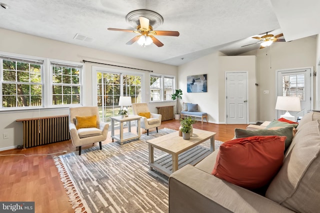 living room with vaulted ceiling, radiator heating unit, baseboards, and wood finished floors