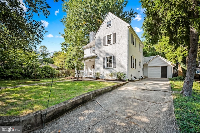 view of front facade featuring a front yard, an outbuilding, fence, stucco siding, and a detached garage