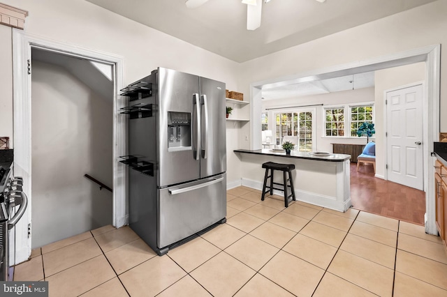 kitchen featuring light tile patterned floors, dark countertops, and stainless steel fridge with ice dispenser