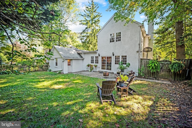 rear view of house featuring stucco siding, a chimney, a yard, a fenced backyard, and a patio area