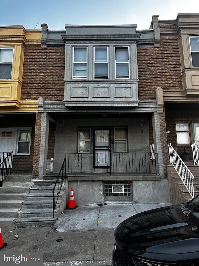 townhome / multi-family property featuring brick siding and covered porch