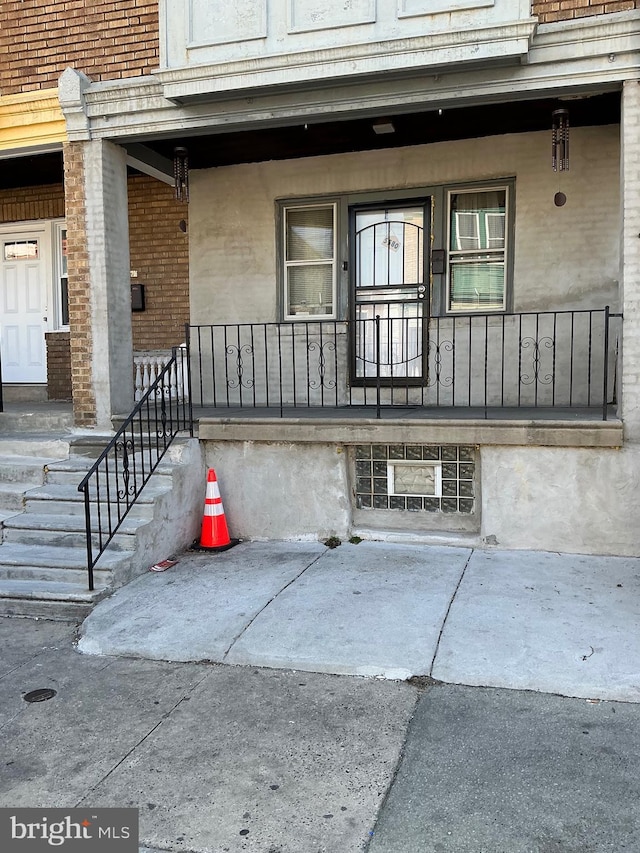 view of exterior entry with brick siding and a porch