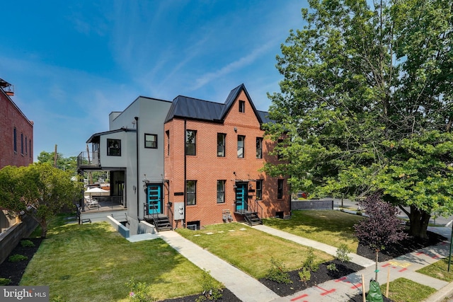 view of front of home featuring a front yard, a standing seam roof, entry steps, brick siding, and metal roof