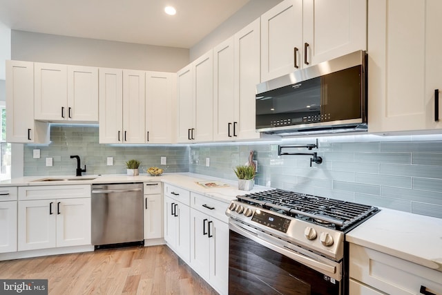 kitchen with white cabinetry, light wood-style flooring, appliances with stainless steel finishes, and a sink