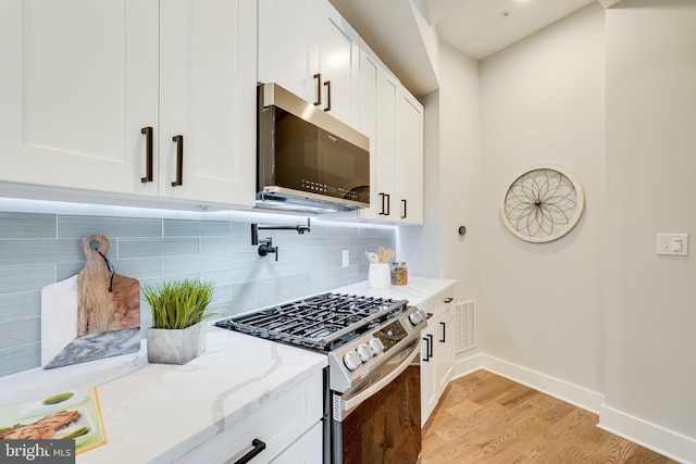 kitchen with light stone counters, visible vents, decorative backsplash, appliances with stainless steel finishes, and light wood-type flooring