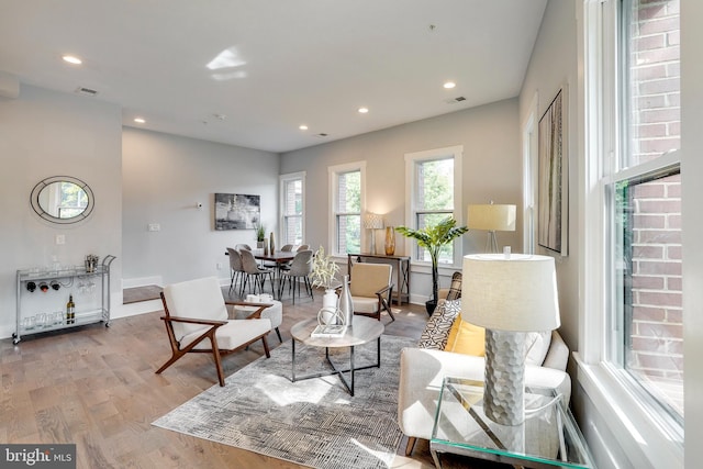 living area with recessed lighting, visible vents, baseboards, and wood finished floors