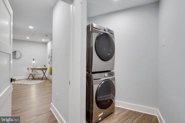 laundry area with baseboards, wood finished floors, laundry area, and stacked washer / dryer