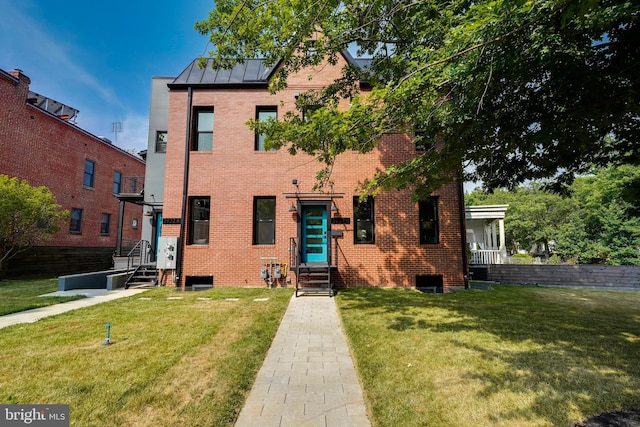 view of front facade with a standing seam roof, a front yard, and brick siding