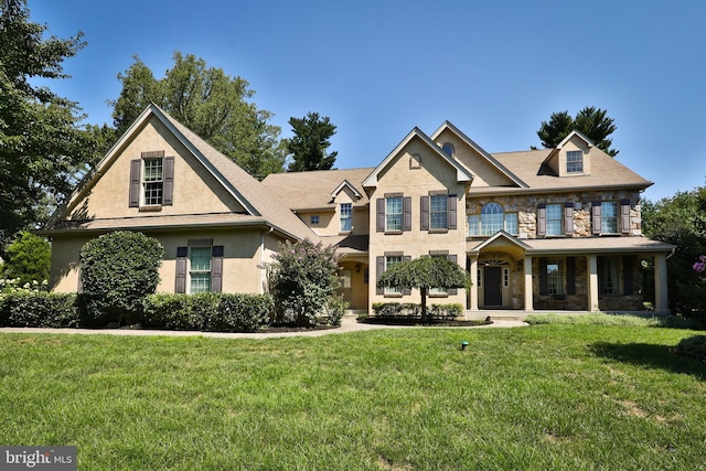 view of front of house featuring stone siding, stucco siding, and a front lawn