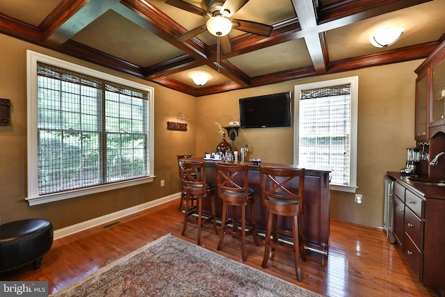 bar with wood finished floors, visible vents, coffered ceiling, a sink, and a bar