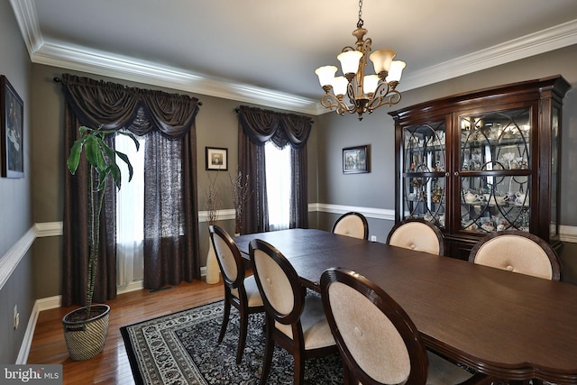 dining room featuring a chandelier, baseboards, wood finished floors, and ornamental molding