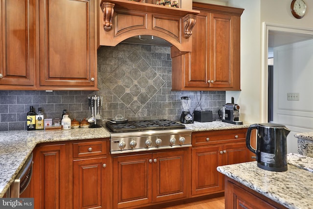 kitchen with decorative backsplash, custom range hood, light stone counters, and appliances with stainless steel finishes