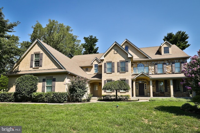 view of front of property featuring a front yard, stone siding, and stucco siding