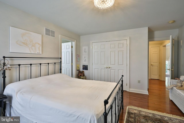 bedroom with visible vents, baseboards, a closet, and dark wood-style floors