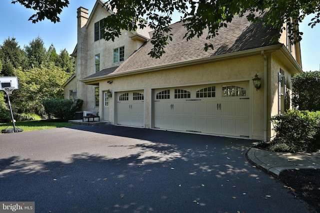 view of property exterior featuring aphalt driveway, a garage, roof with shingles, and stucco siding