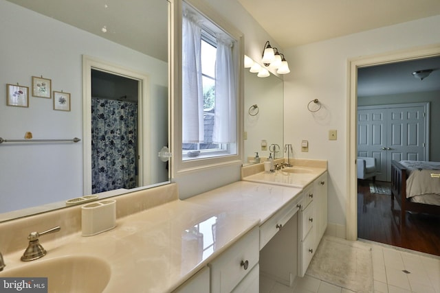 ensuite bathroom featuring ensuite bath, double vanity, tile patterned flooring, and a sink