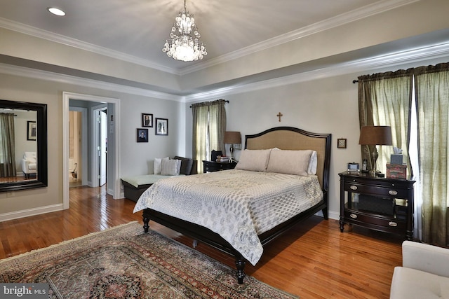 bedroom featuring baseboards, crown molding, an inviting chandelier, and wood finished floors