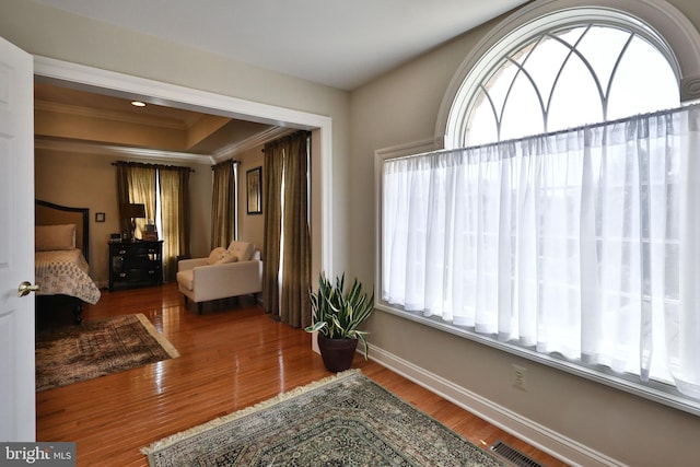 bedroom with visible vents, ornamental molding, baseboards, and wood finished floors