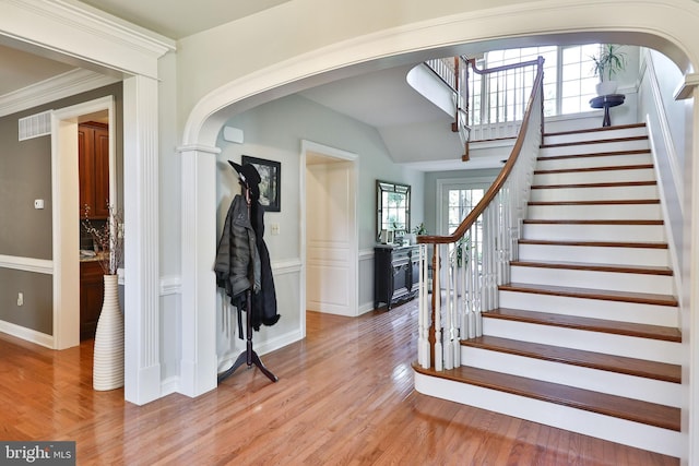 foyer entrance featuring visible vents, arched walkways, and light wood-style flooring